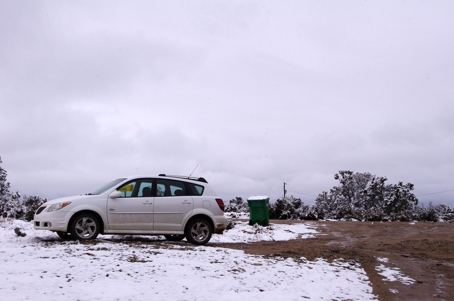 Car parked on a muddy, snowy road in Taos